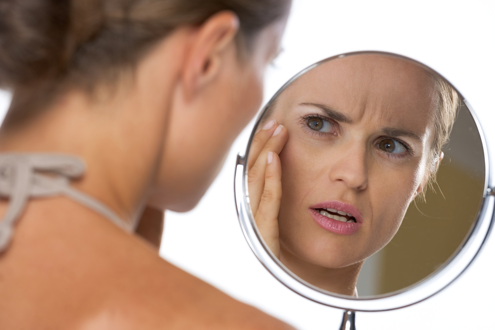 OROGOLD - Young woman concernedly looking in the mirror