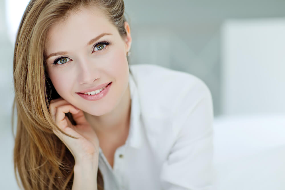 Smiling woman in white with chin resting on hand