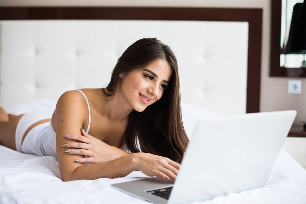 Smiling woman chatting online on her bed